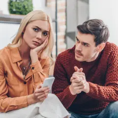 Kobieta z telefonem na twarzy, mężczyzna zaniepokojony. Czy to zazdrość o byłych partnerów?