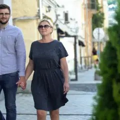 Para spaceruje ulicą, trzymając się za ręce. Młodszy mężczyzna w okularach i starsza kobieta pokazują, że różnica wieku w związku nie jest przeszkodą.