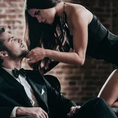 Elegancka dziewczyna leży na chłopaku w garniturze, dotykając jego podbródka.