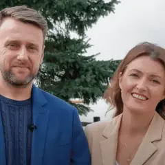 Uśmiechnięta para, on w niebieskiej marynarce, ona – żona z Ukrainy – w beżowej.