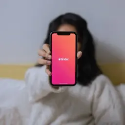 Osoba trzyma telefon z aplikacją Tinder. Chcesz wiedzieć, jak zmienić wiek na Tinderze?