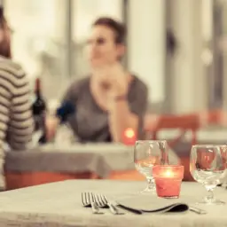 Para samotne dziewczyny po 30. randka w restauracji. Dwa kieliszki, świeca i sztućce na stole.