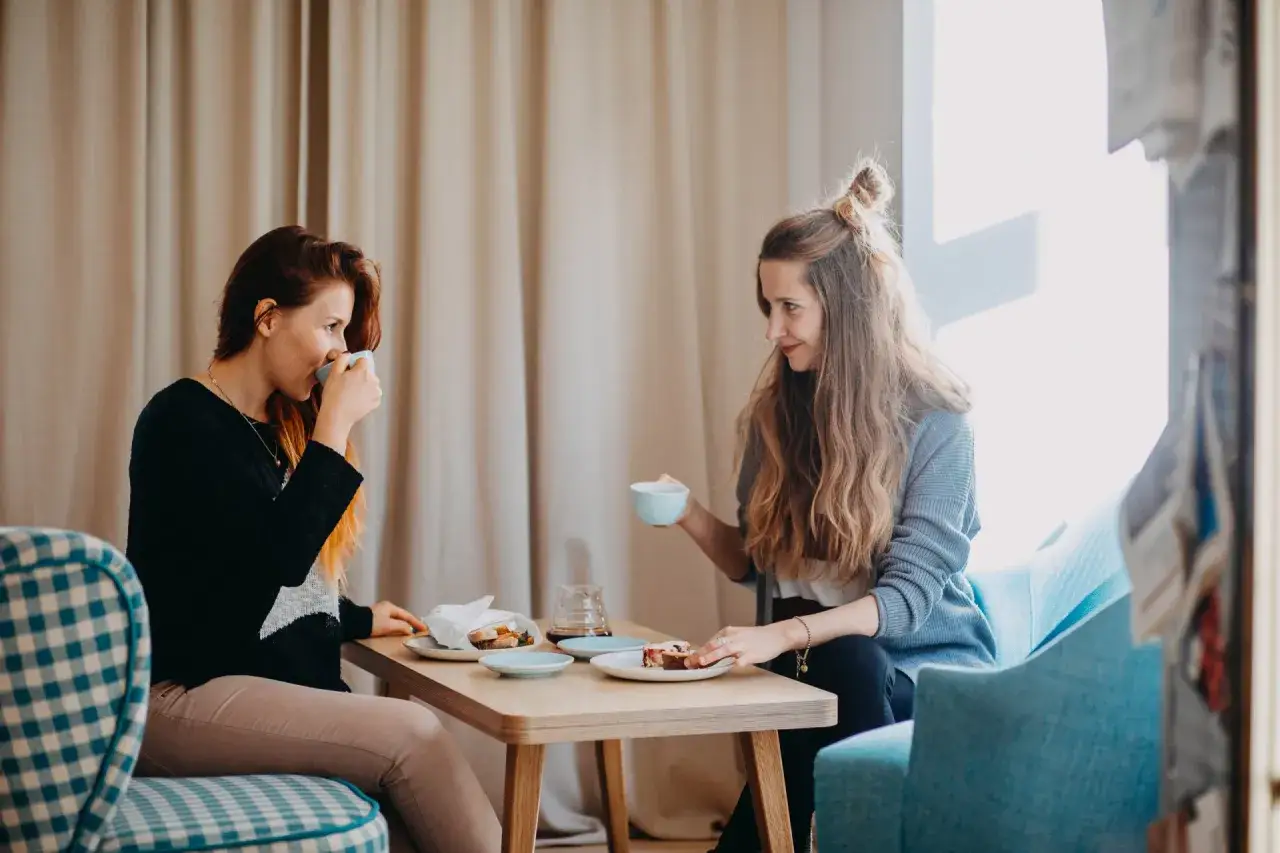 Dwie kobiety piją kawę i jedzą ciasto. Idealny moment na luźną rozmowę i wymianę tekstów na rozpoczęcie rozmowy.